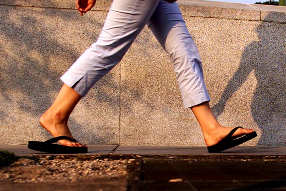 A woman walks with flip flops in Washington, July 15, 2003. Flip-flops in the nation's capital typically mean politicians switching positions on an important issue like abortion or taxes, but not this summer. Instead, the flip-flop resonating in Washington and across the country is the snapping sound coming from women's feet as they adopt thong sandals as the comfortable shoes to wear to work, on a hot date or just to the grocery store. Picture taken July 15, 2003. NO RIGHTS CLEARANCES OR PERMISSIONS ARE REQUIRED FOR THIS IMAGE REUTERS/William Philpott/FEATURE-LIFE-FLIPFLOPS WP/HB - RTRTFB