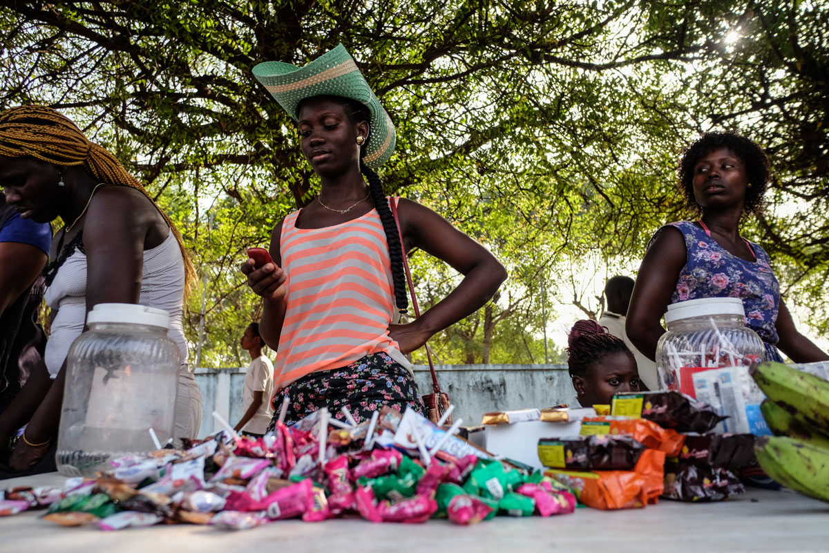 A woman selling sweets on the  a green cowboy hat sells candy on the sidelines of Bissau's carnival, wears a rather stunning green cowboy hat. [Ricci Shryock/Al Jazeera]